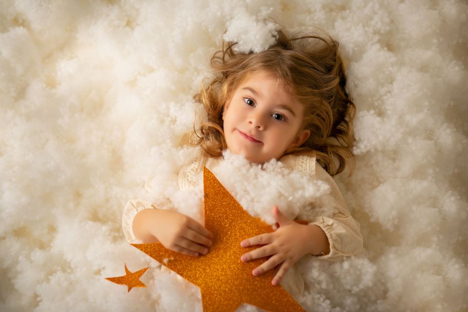 Bambina fra le nuvole di ovatta con una stella marina
