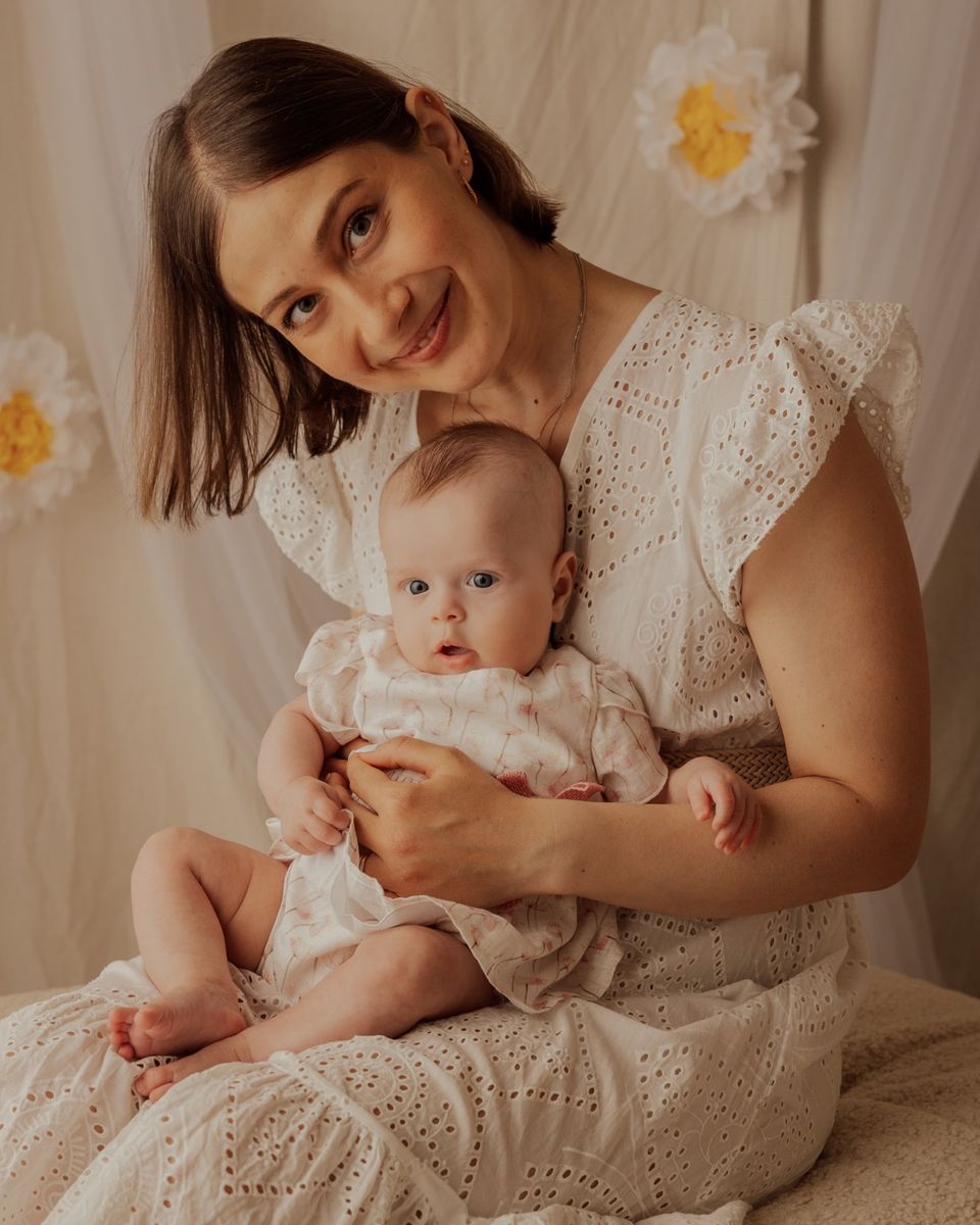 Mamma sorridente con la bambina in braccio, luce di studio