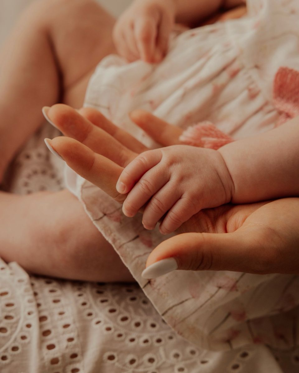 La manina di una neonata appoggiata sulla mano di un adulto