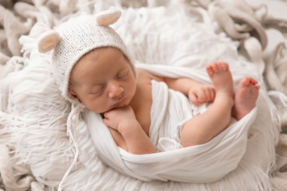 Neonato addormentato con cappellino bianco