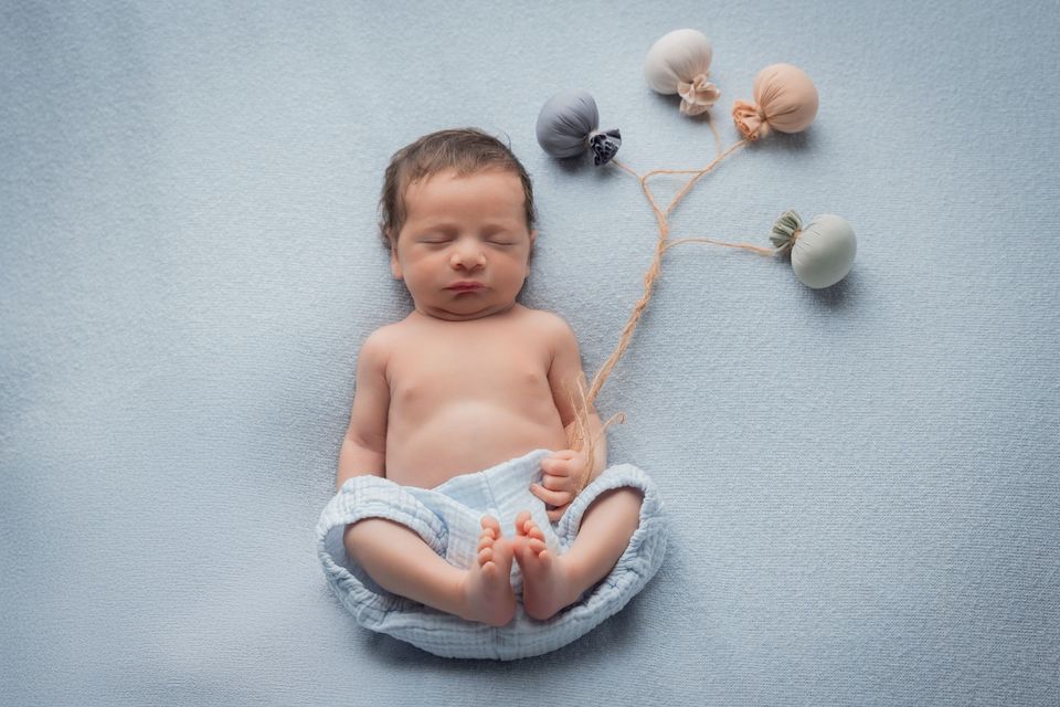 Neonato disteso accanto a piccole palline di lana