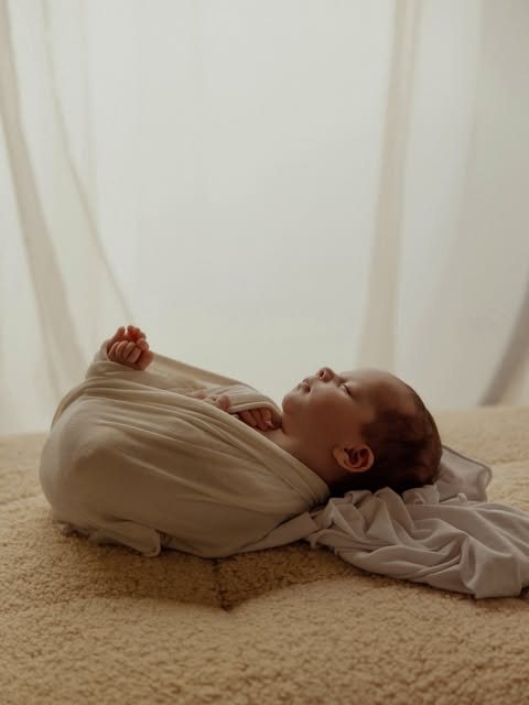 Neonato avvolto che dorme su fondo chiaro