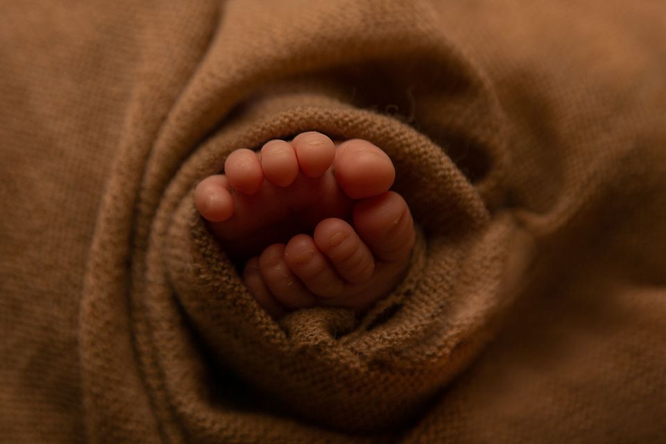 Piedini di neonato avvolti in un telo marrone