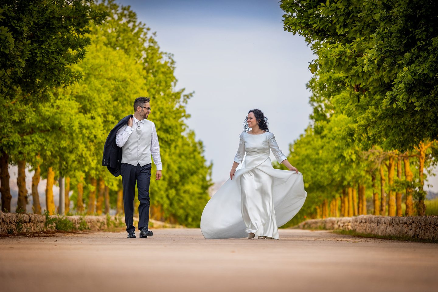 Abito della sposa mosso dal vento lungo un viale